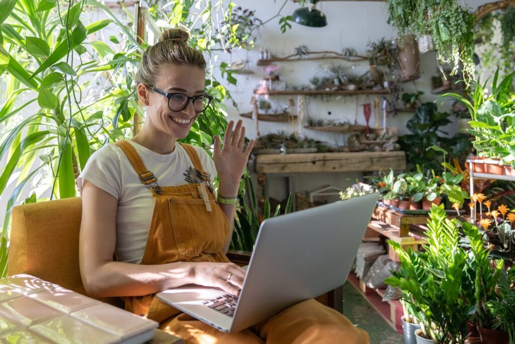 young woman waving while video conferencing laptop home 2